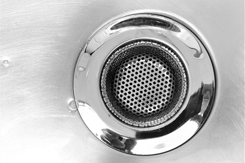 Close-up of a stainless steel sink with a perforated drain strainer.